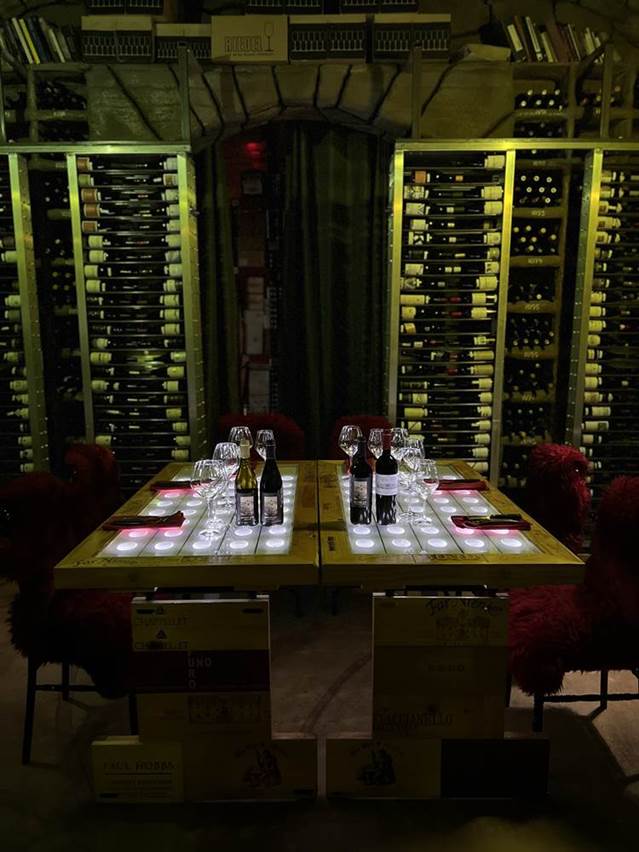 A table with wine bottles and glasses  Description automatically generated