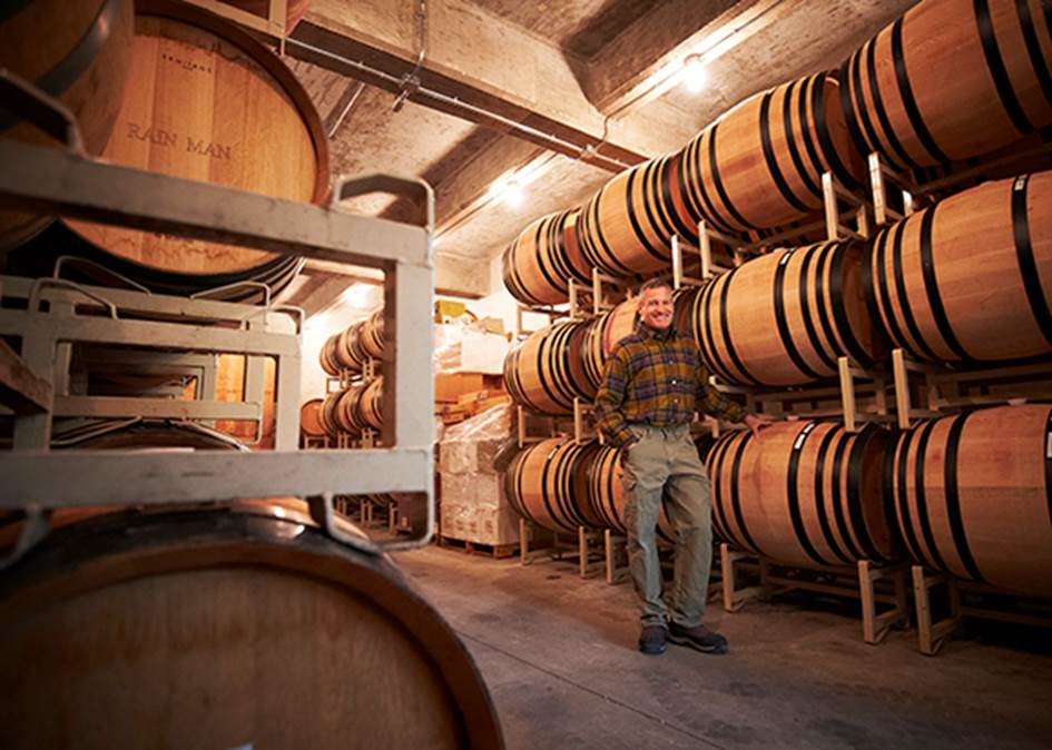 A person standing in a room with barrels  Description automatically generated