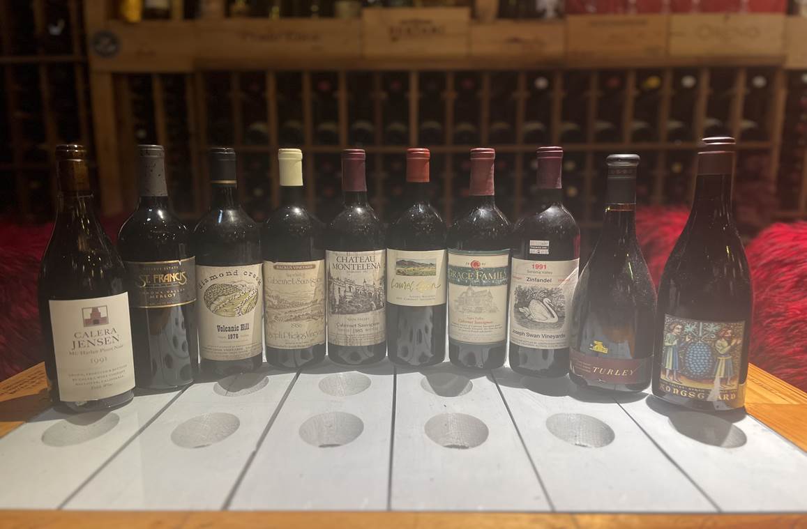 A row of wine bottles on a table  Description automatically generated