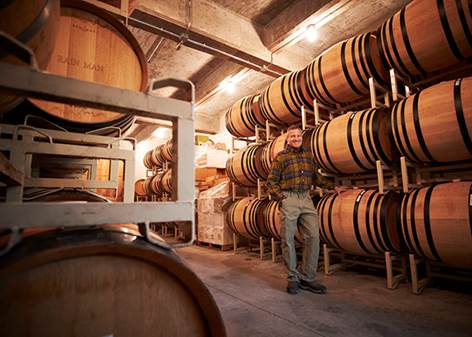 A person standing in a room with barrels  Description automatically generated