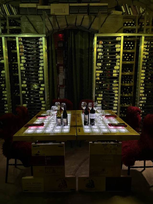 A table with wine bottles and glasses  Description automatically generated