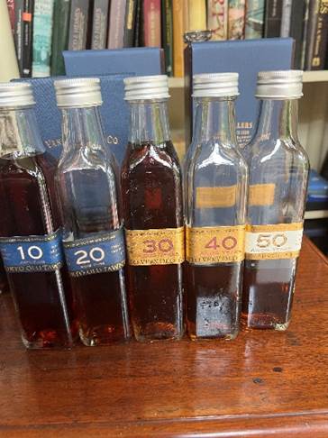 A group of bottles with brown liquid  Description automatically generated