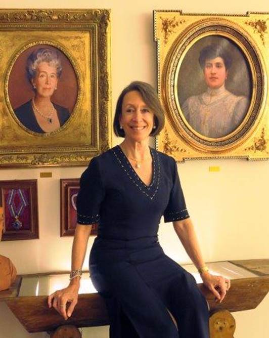 A person sitting on a bench with a couple of portraits of a person  Description automatically generated