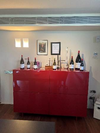 A red cabinet with bottles of wine on it  Description automatically generated